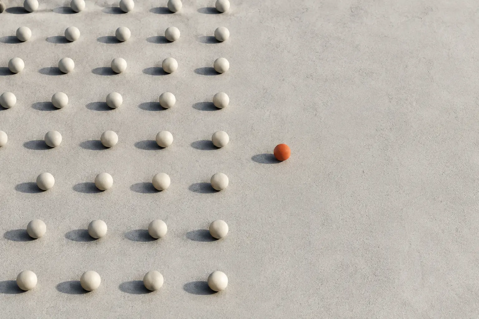 An orange ball standing apart from rows of neutral balls